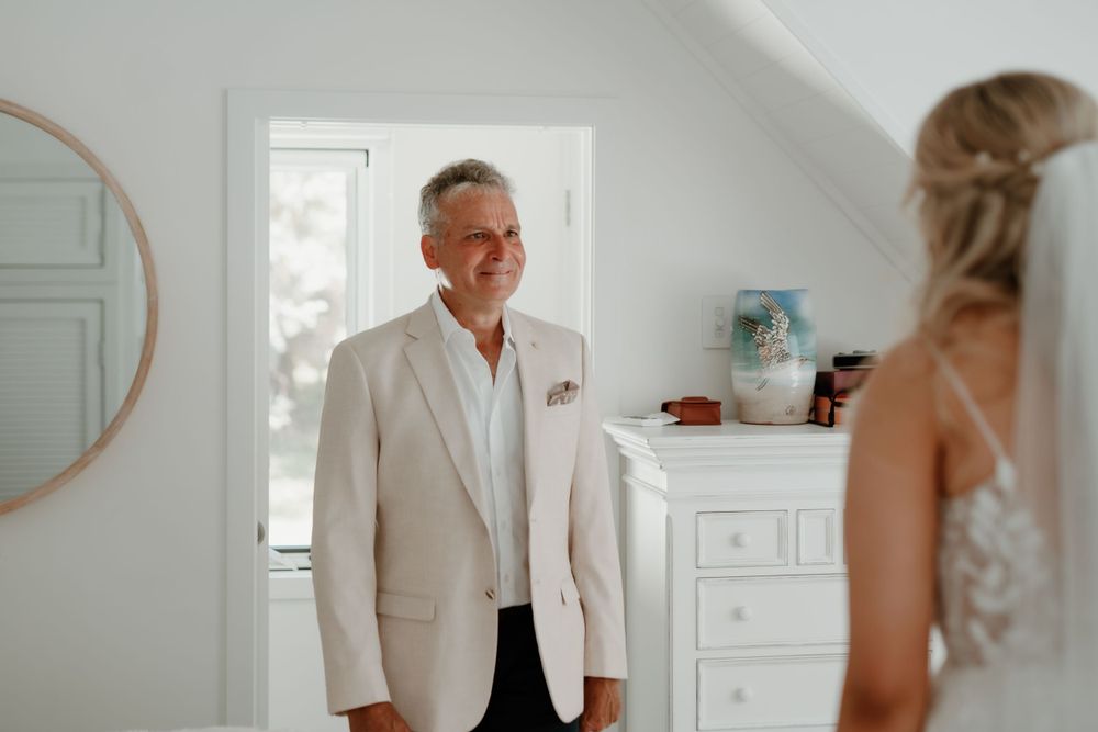 First look moment captured between couple in bright white room.