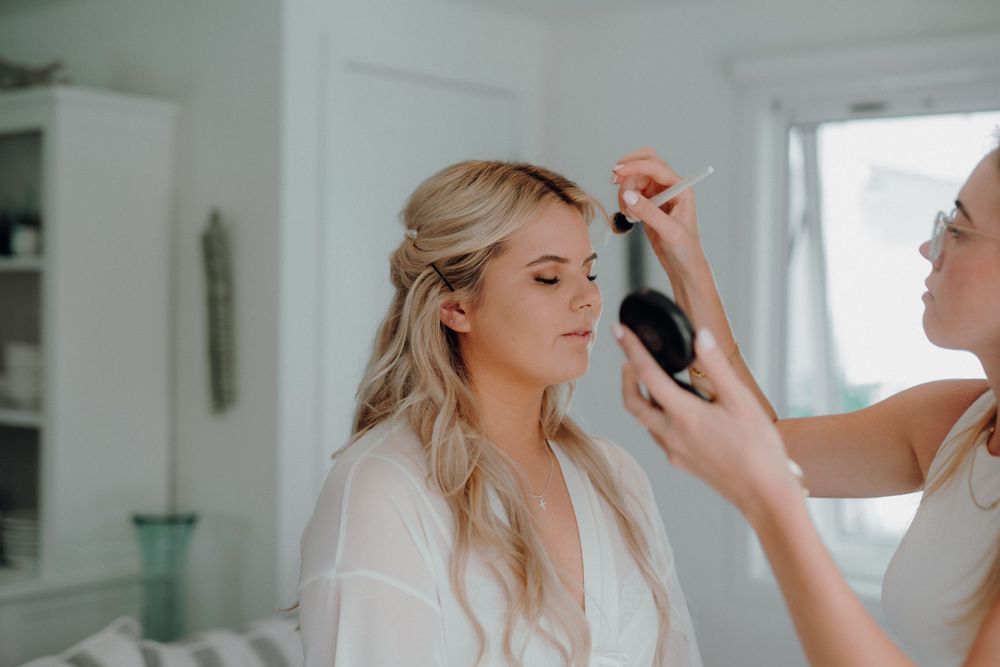 Getting ready scene with makeup application in bright white room.