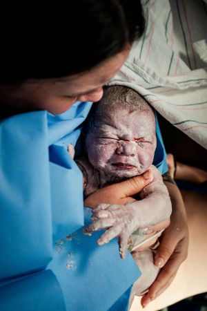 Healthcare providers caring for a newborn in a delivery room setting.