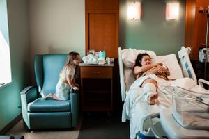 Hospital room scene showing supportive moments during labor with teal medical chairs.