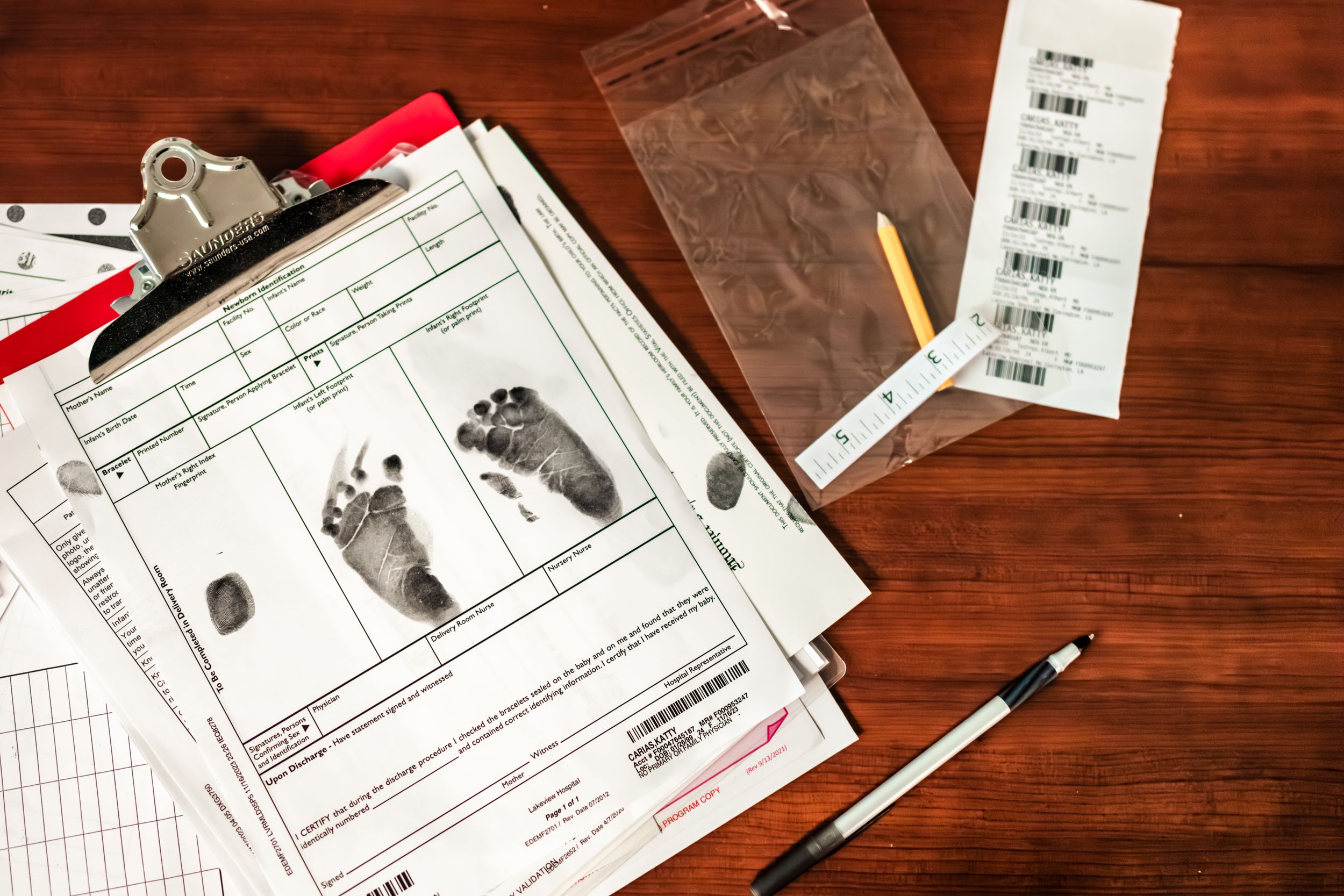 Medical forms and footprint documentation laid out on wooden desk surface.