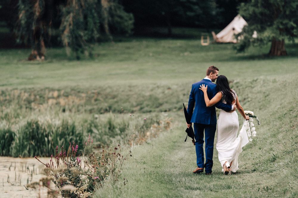 A candid reportage portrait of bride and groom walking through the grounds are Cowley Manor holding hands