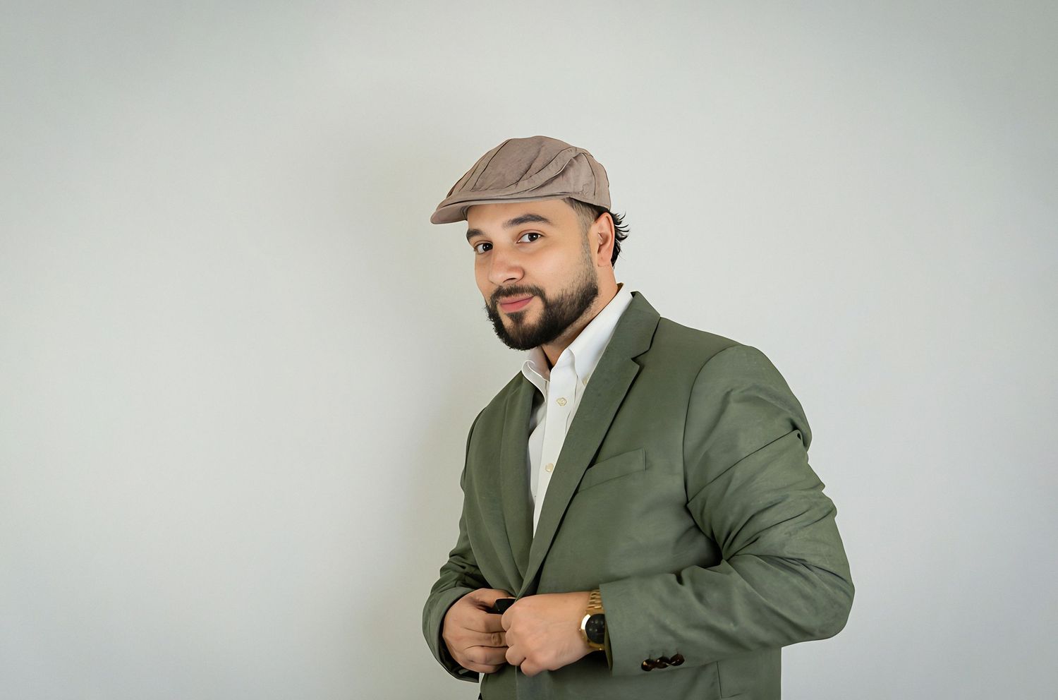 Portrait of a person wearing a green blazer and flat cap looking confidently at the camera.