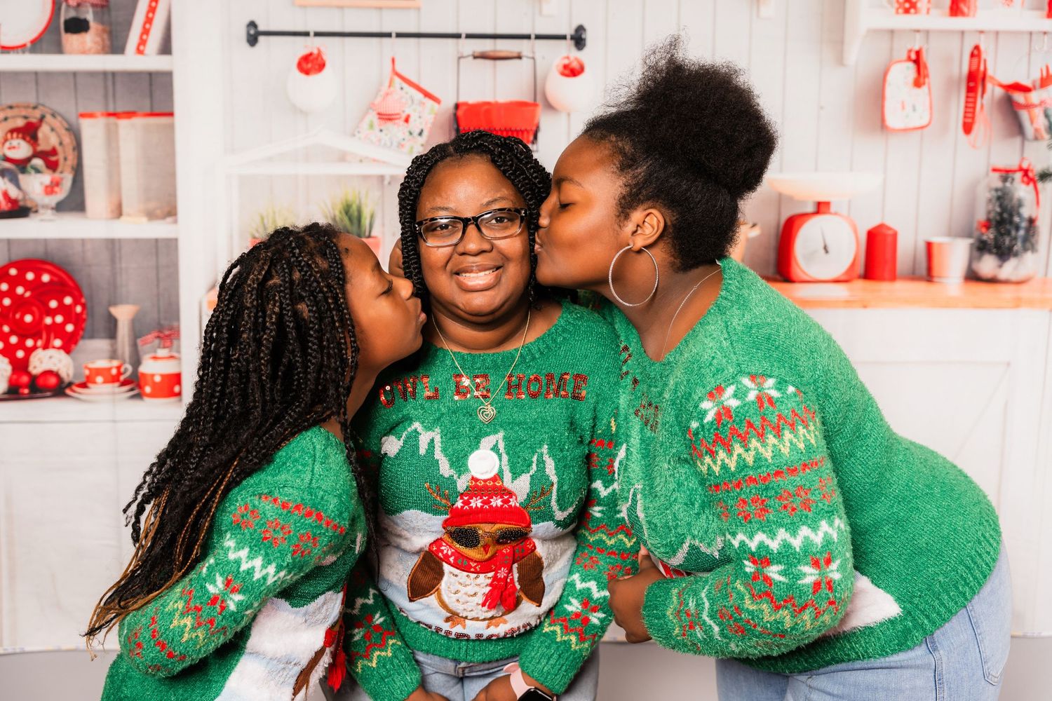 Three people in matching green Christmas sweaters share a sweet family moment during the holidays.