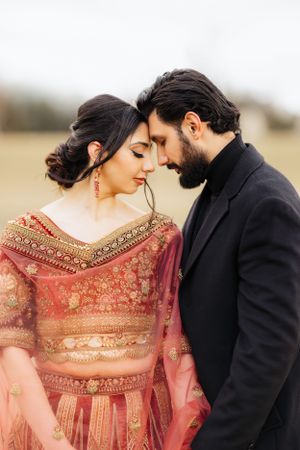 A romantic couple in traditional attire shares an intimate moment in a field.