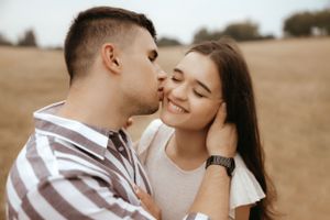 A romantic couple shares an intimate moment in a sunlit field.