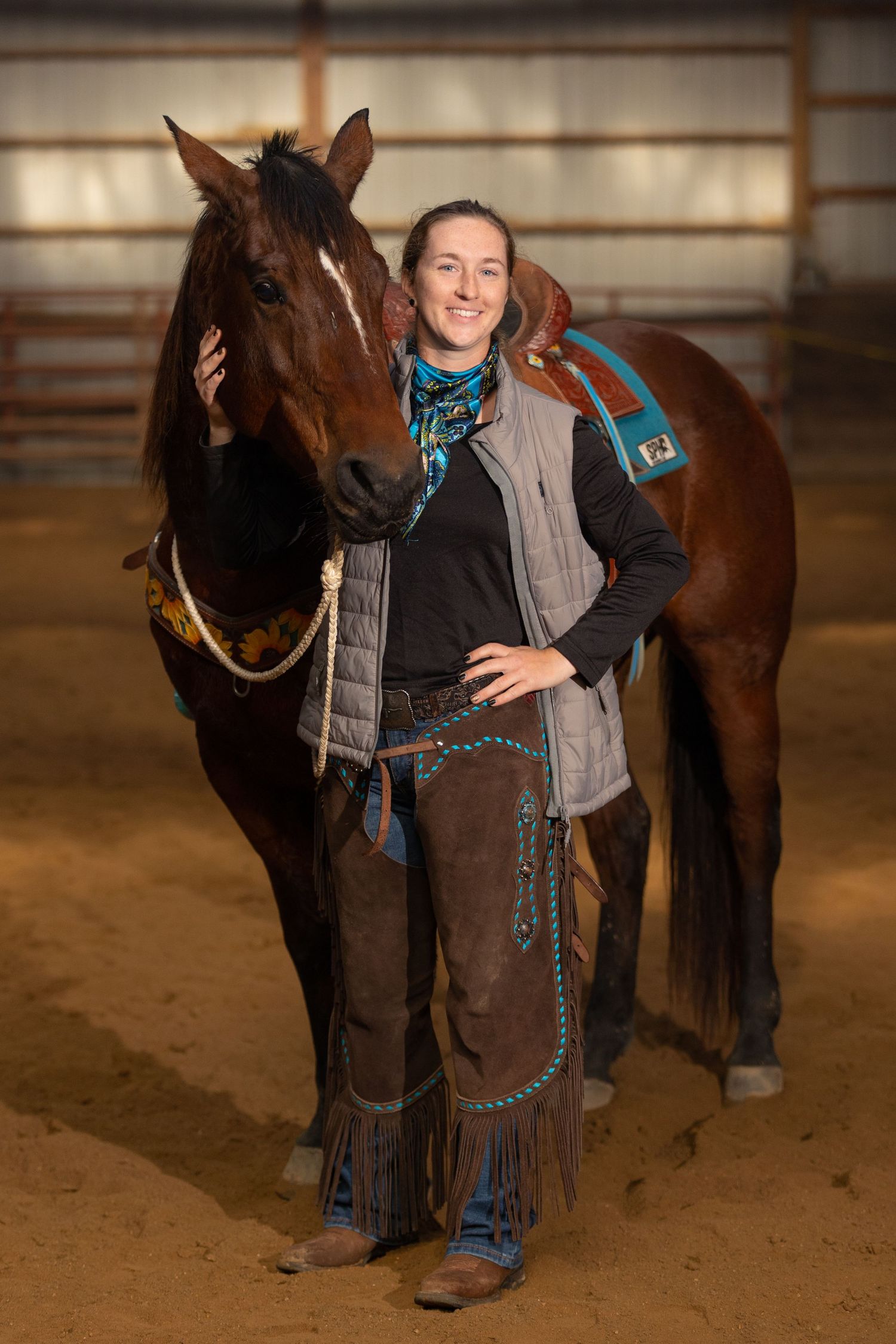 A cowgirl proudly poses with her horse inside the riding arena at Coyote Creek Tack and Stables in Sigel, Illinois.