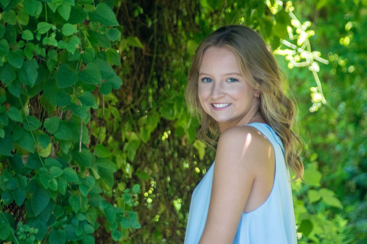 Summer portrait in lush green garden setting with soft natural lighting.
