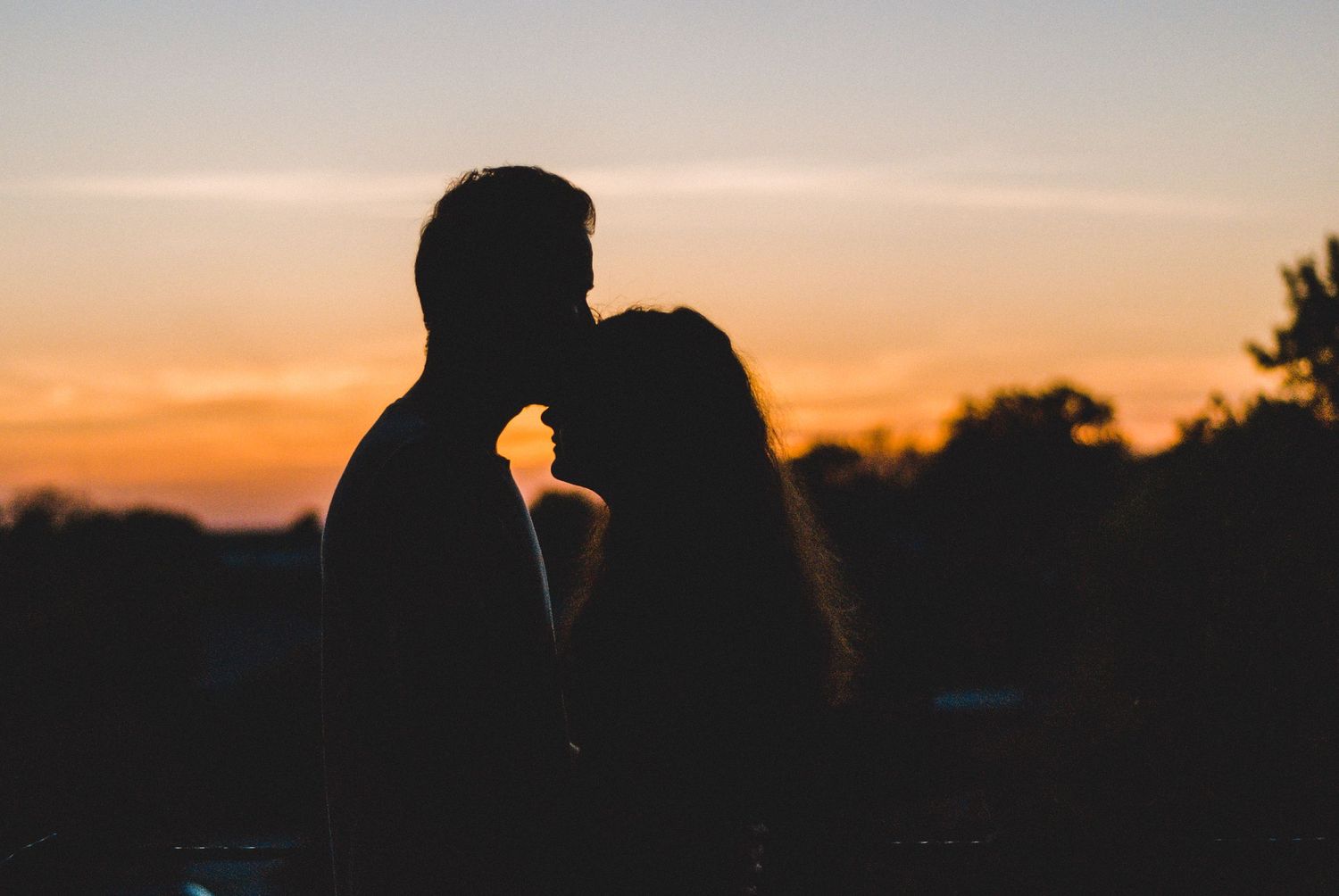 Man kissing woman's forhead at sunset in parking garage in downtown Greenville, South Carolina