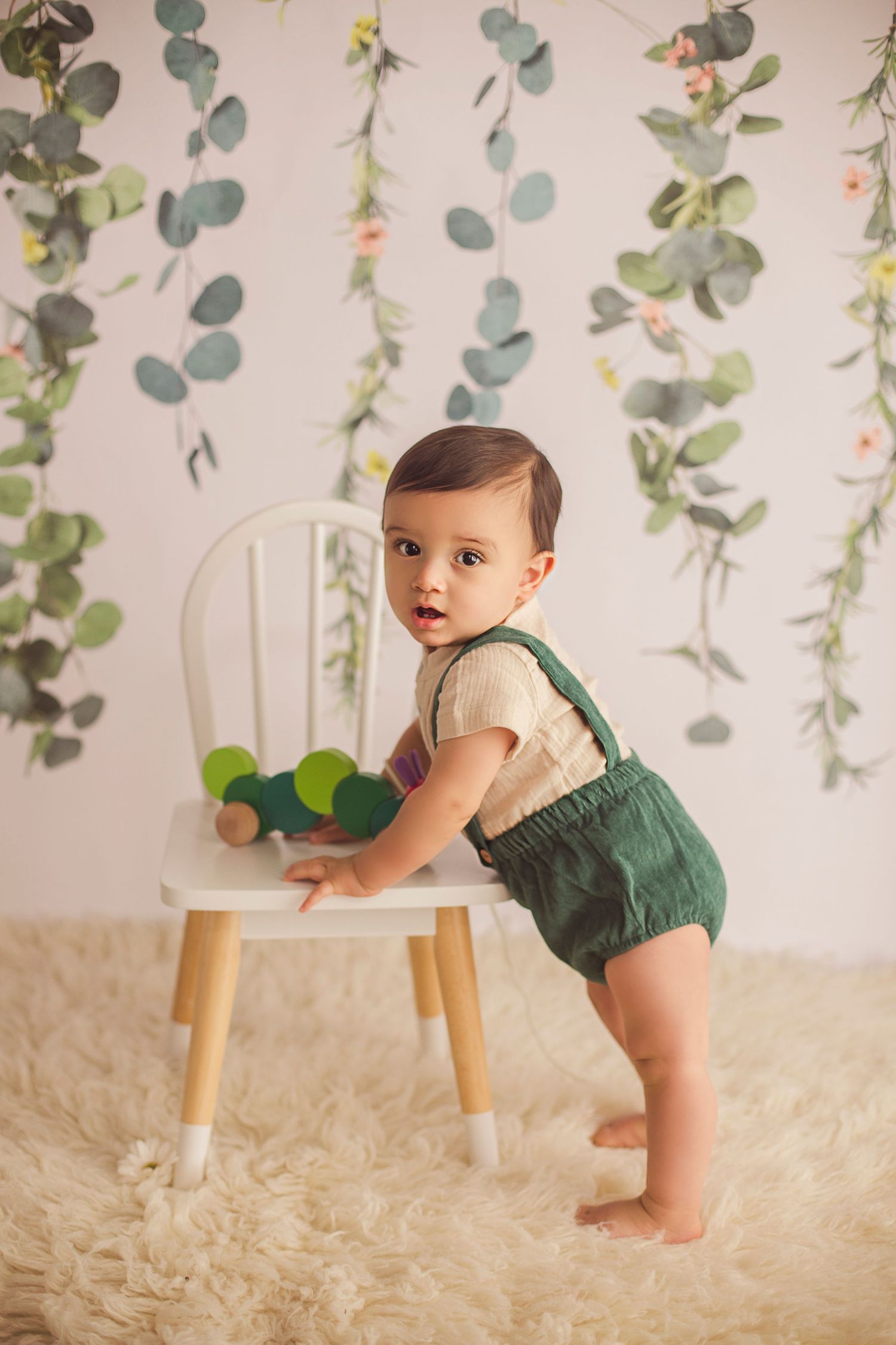 9 months old baby boy holding on to a white wooden chair