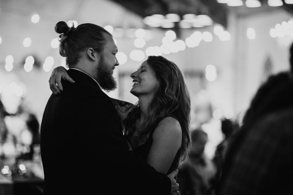 Black and white photo of a bearded man and woman sharing an intimate dance at a wedding reception.