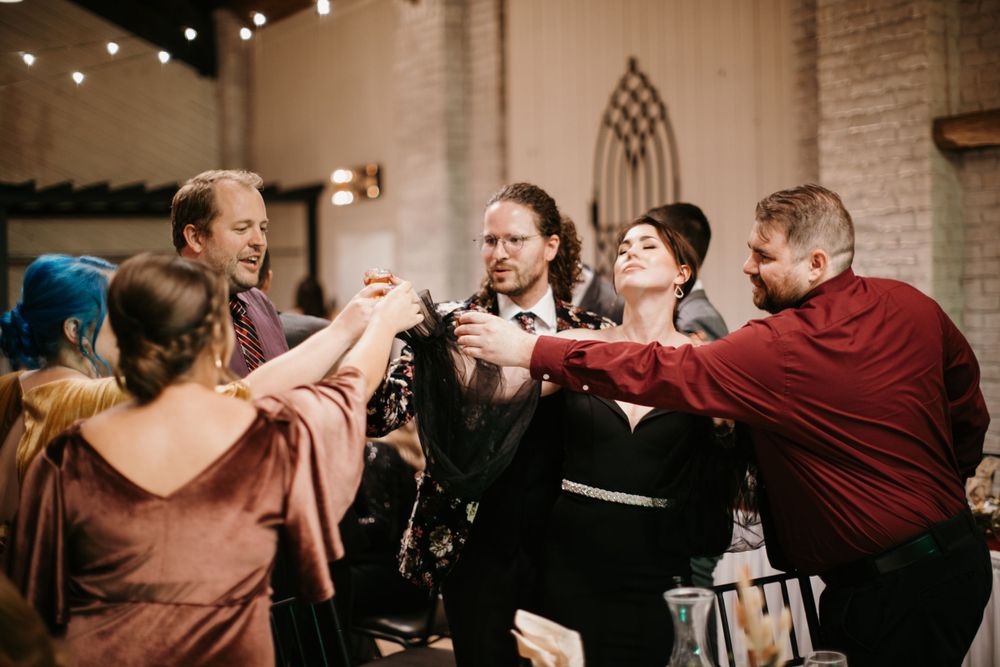 Lively group of wedding guests celebrate together on the dance floor at a festive reception.
