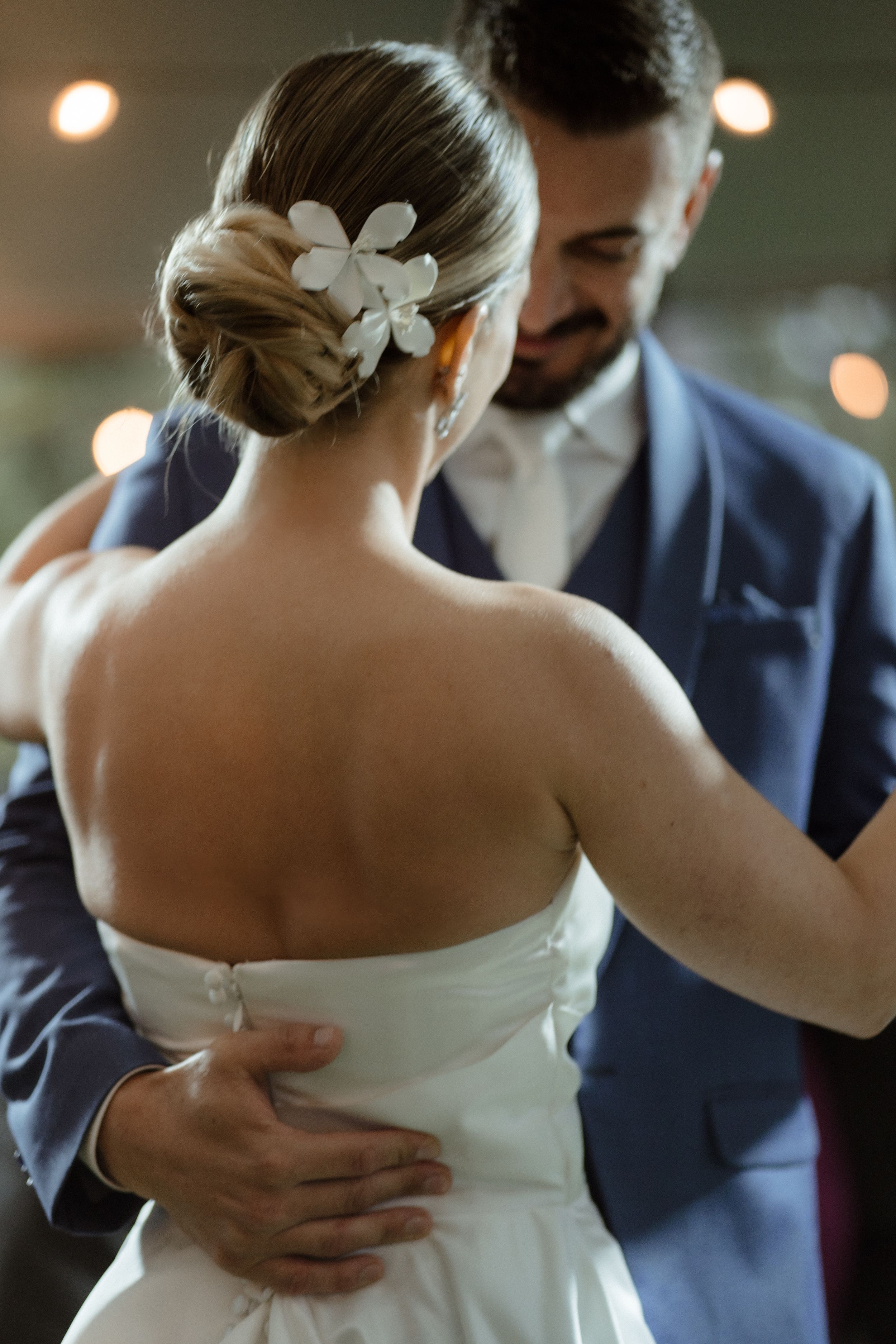 Elegant wedding hairstyle adorned with white flowers as couple shares an intimate moment.