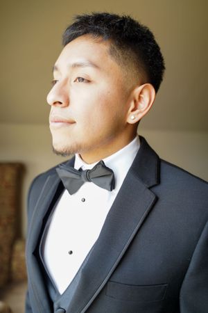 Close-up profile shots of a groom in a classic black tuxedo and bow tie getting ready for his wedding day.