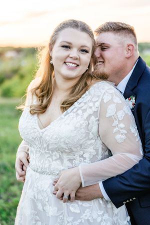 Romantic wedding portraits of couple embracing in golden hour light wearing formal attire.