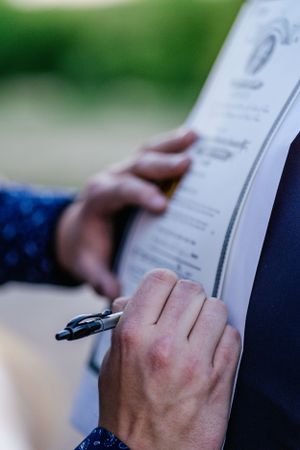 Hands signing official documents with a pen on white paper.