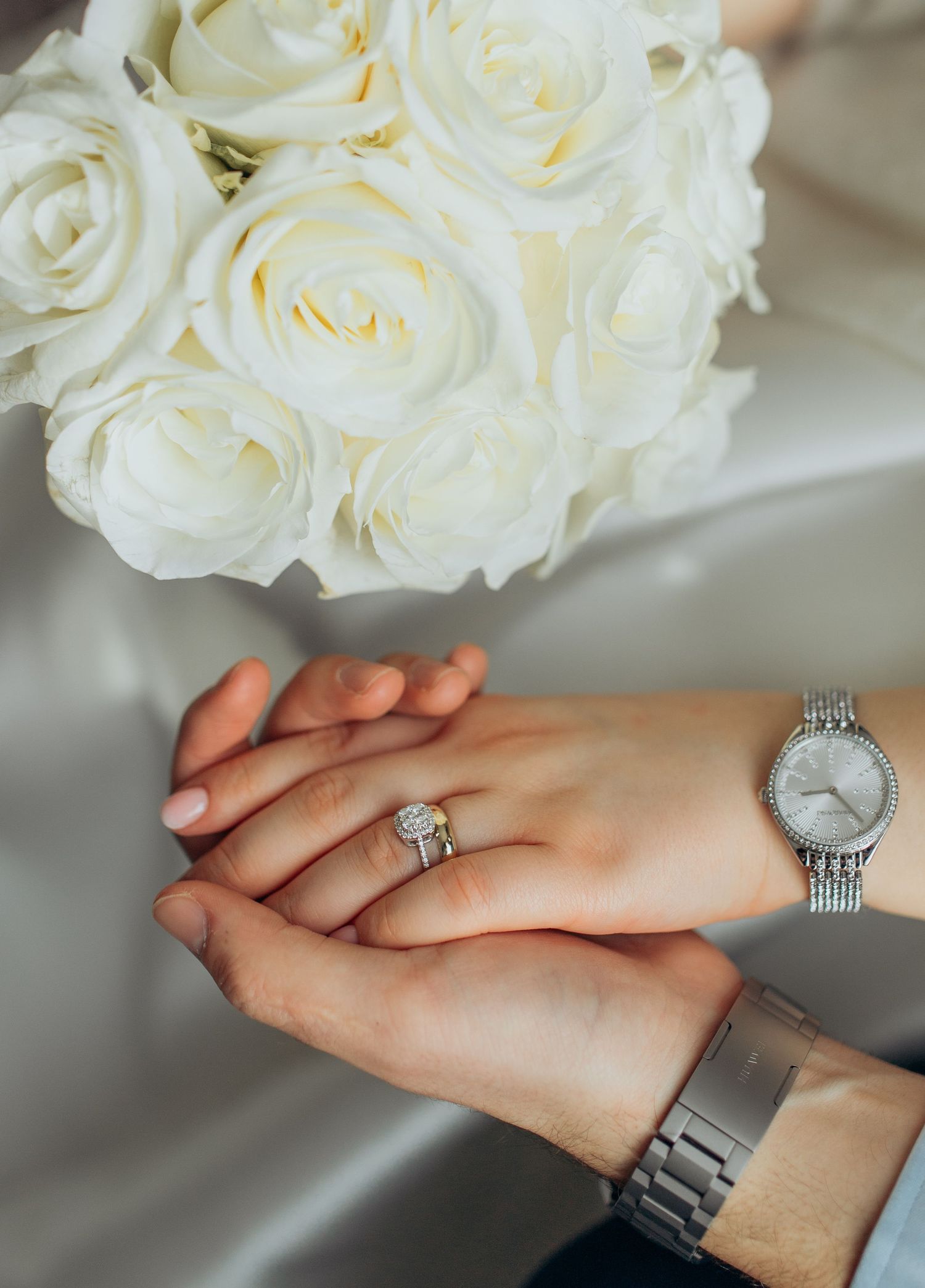 White rose bouquet with engagement ring and watch display on hands.