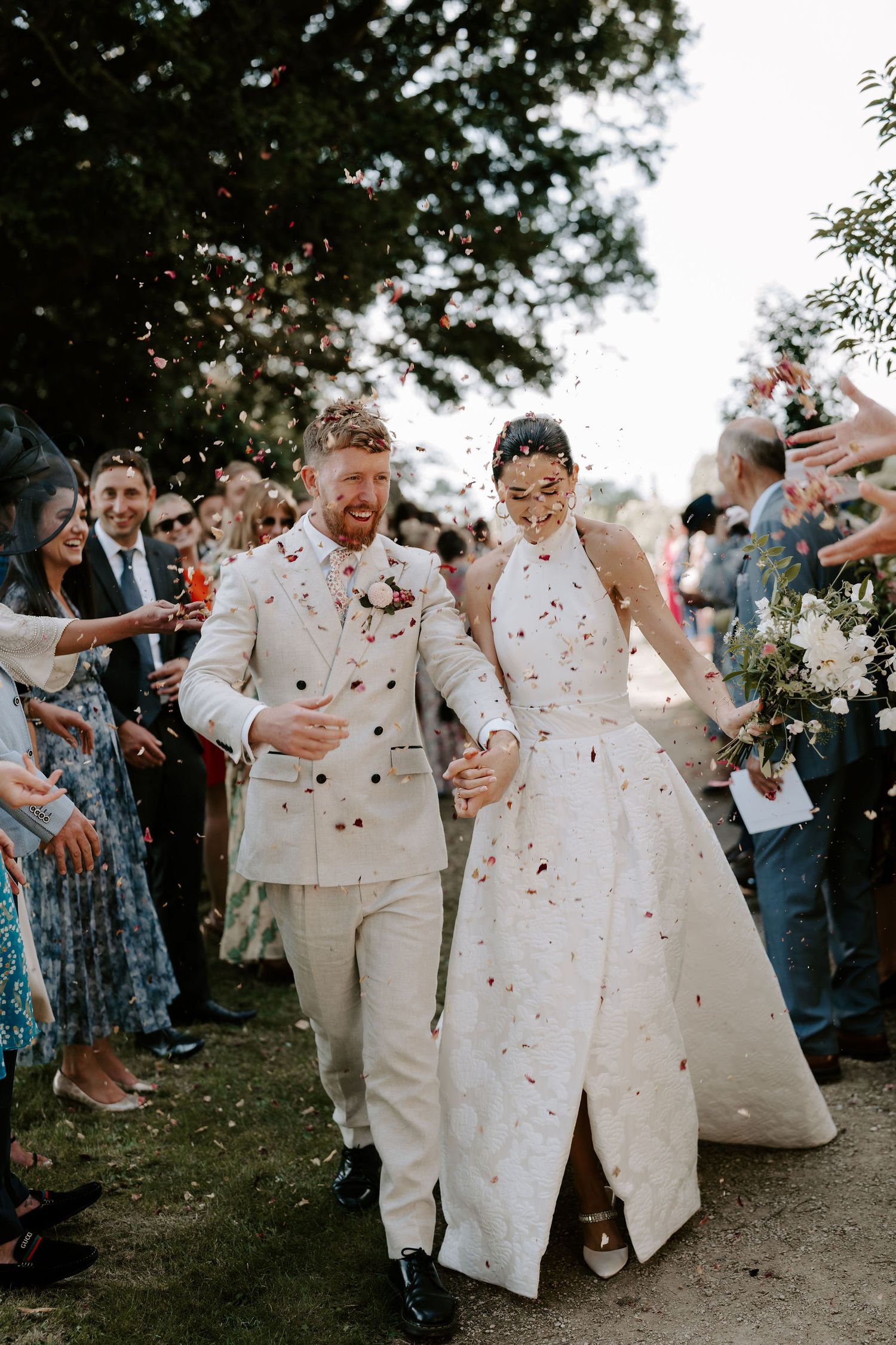 bride and groom walking through the wedding guests throwing confetti petals at st Nicholas church in Oxfordshire
