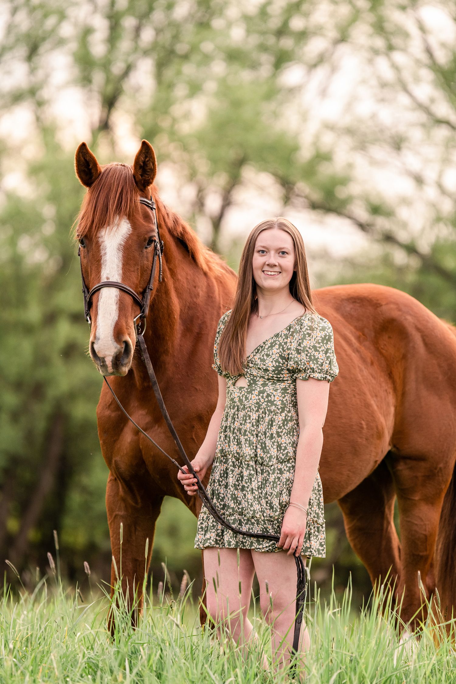 Girl in a green floral dress standing with a chestnut Thoroughbred