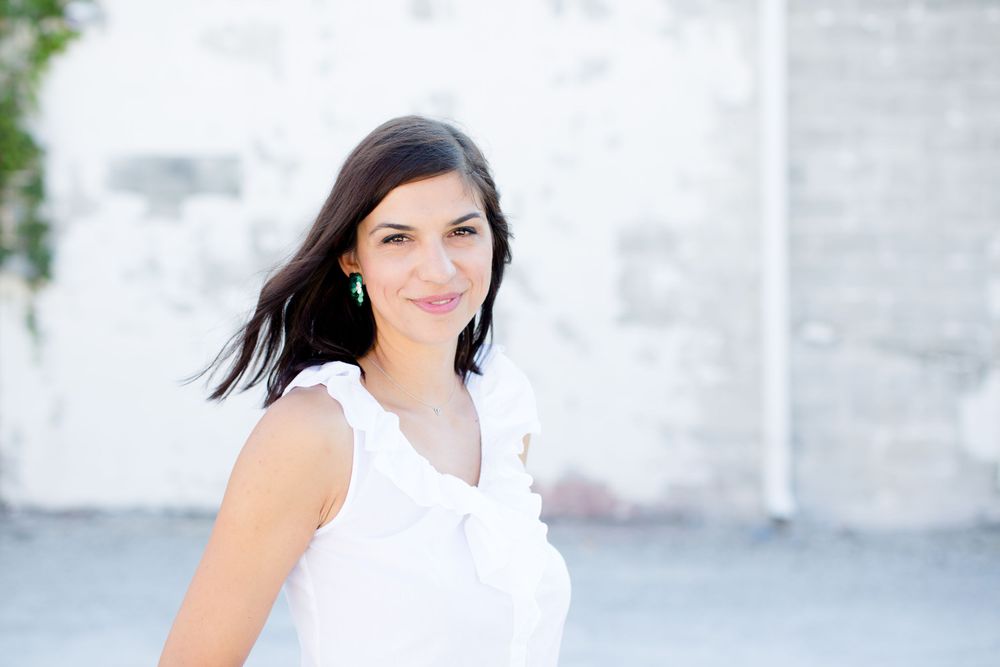 Woman in white sleeveless top with dark hair against light background.
