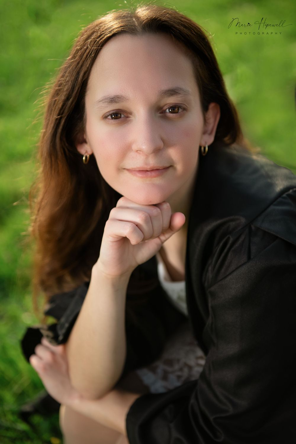 Portrait of a person in black sweater with thoughtful expression against green background.
