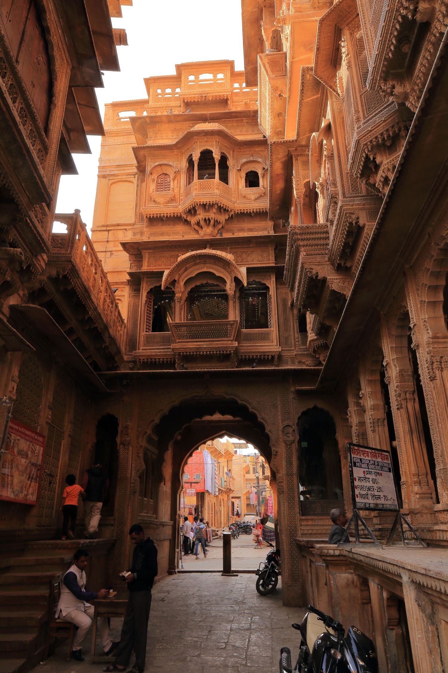 Historic sandstone archway and buildings in narrow street of Jaisalmer's old city.