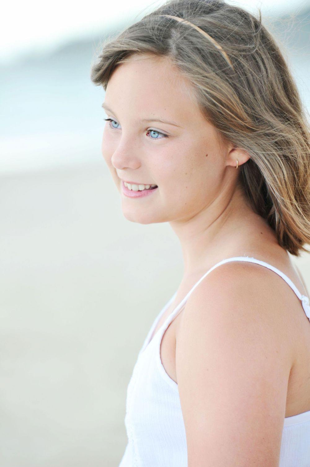 Blue eyed tween girl gazing out to sea at the beach