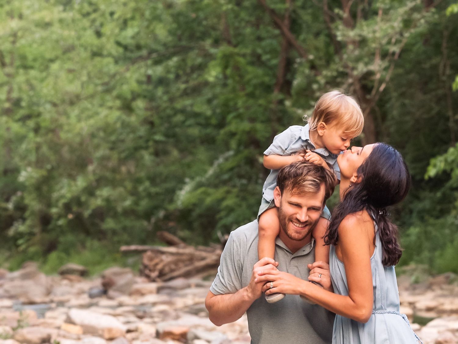 Summer outdoor family photography boy on dad's shoulders kissing mom