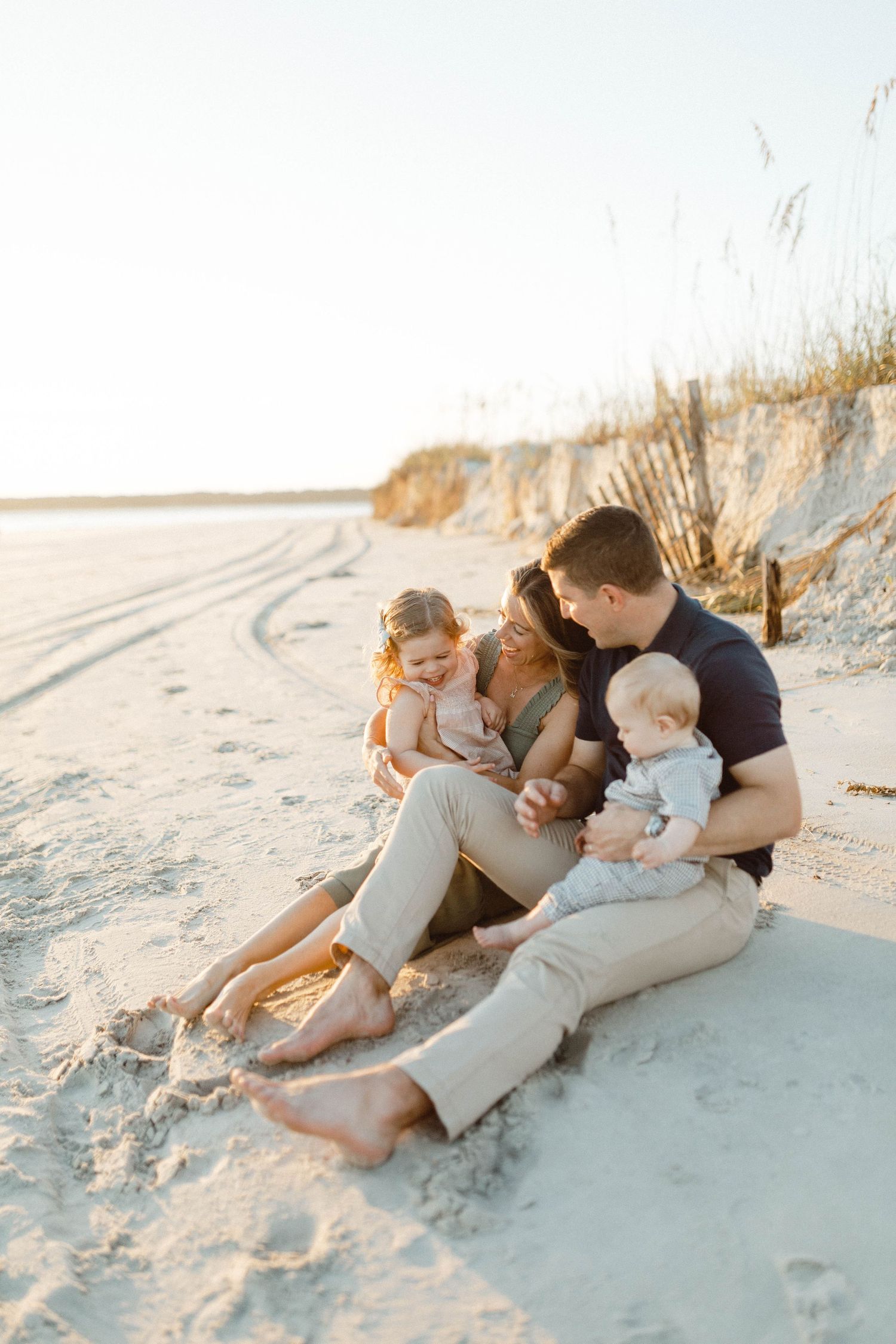 A photo by B. Logsdon of a young family spending a warm evening together sitting on a sandy Hilton Head beach at sunset.