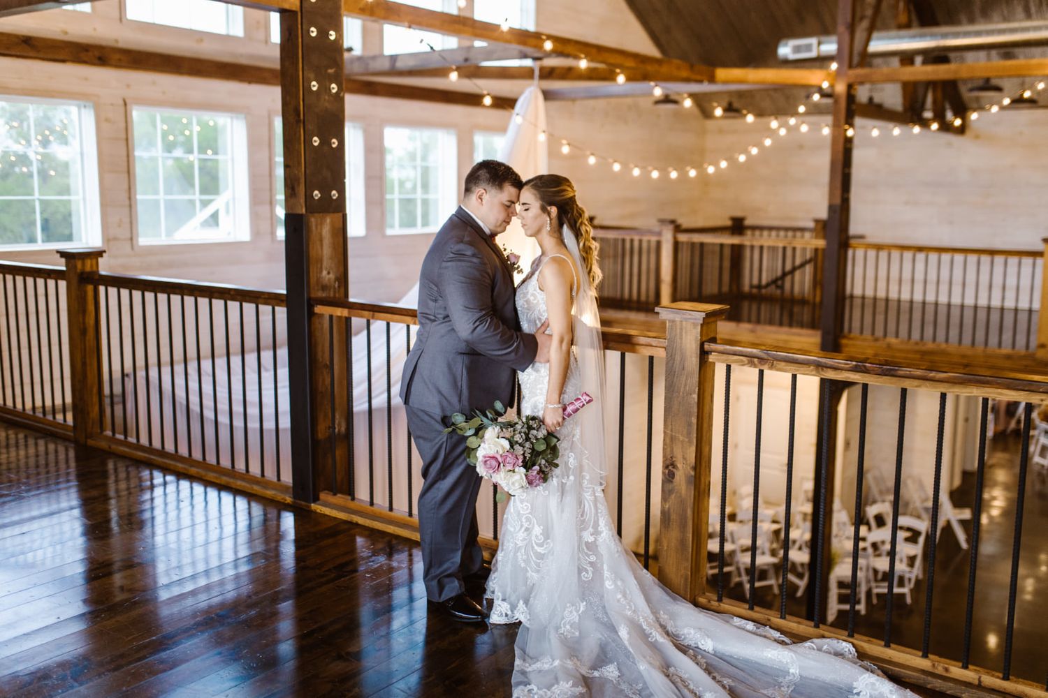 Couple shares intimate moment on rustic wooden balcony under romantic string lights.