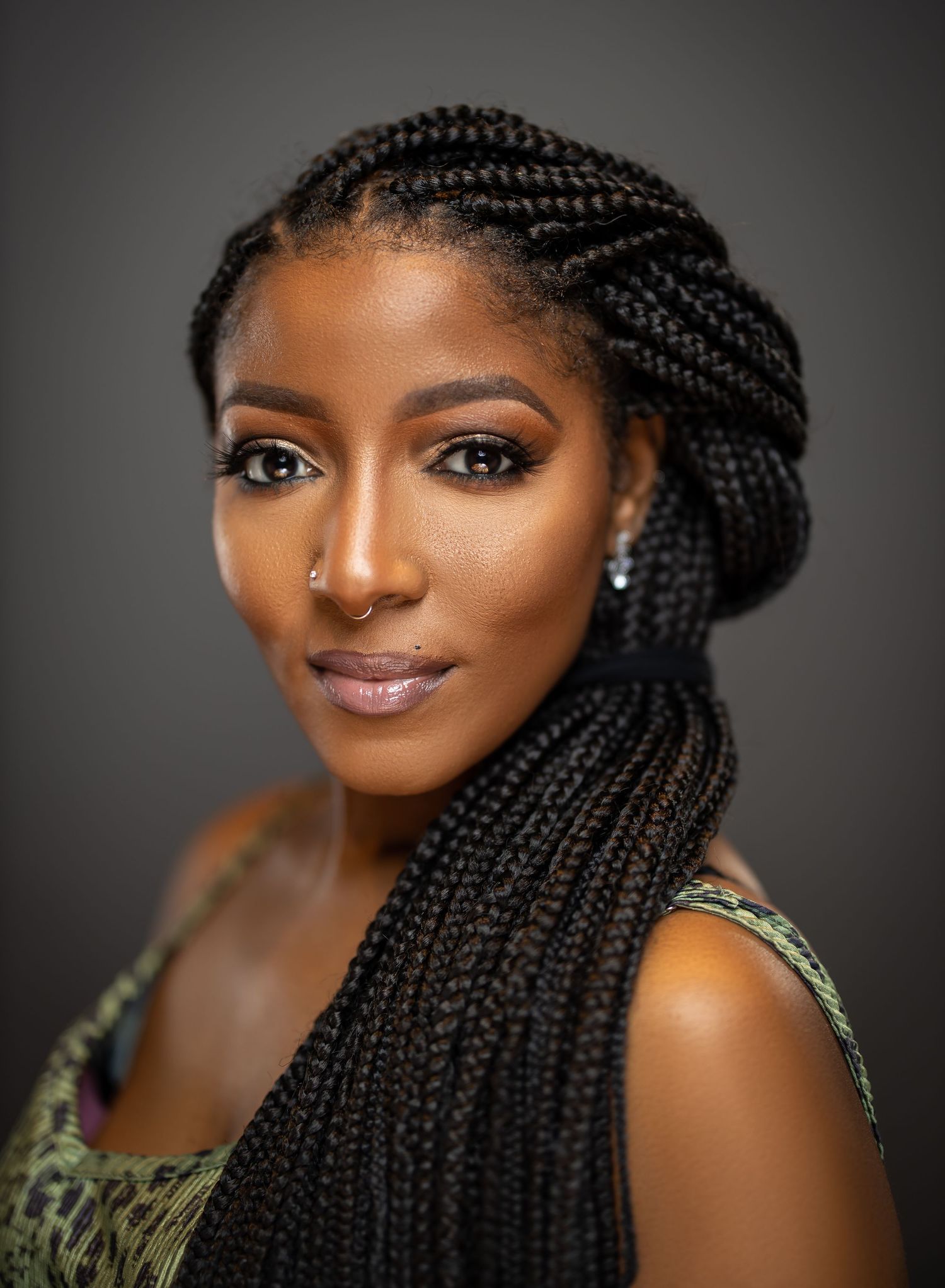 Beautiful portrait highlighting intricate braided hairstyle and elegant makeup against dark background.