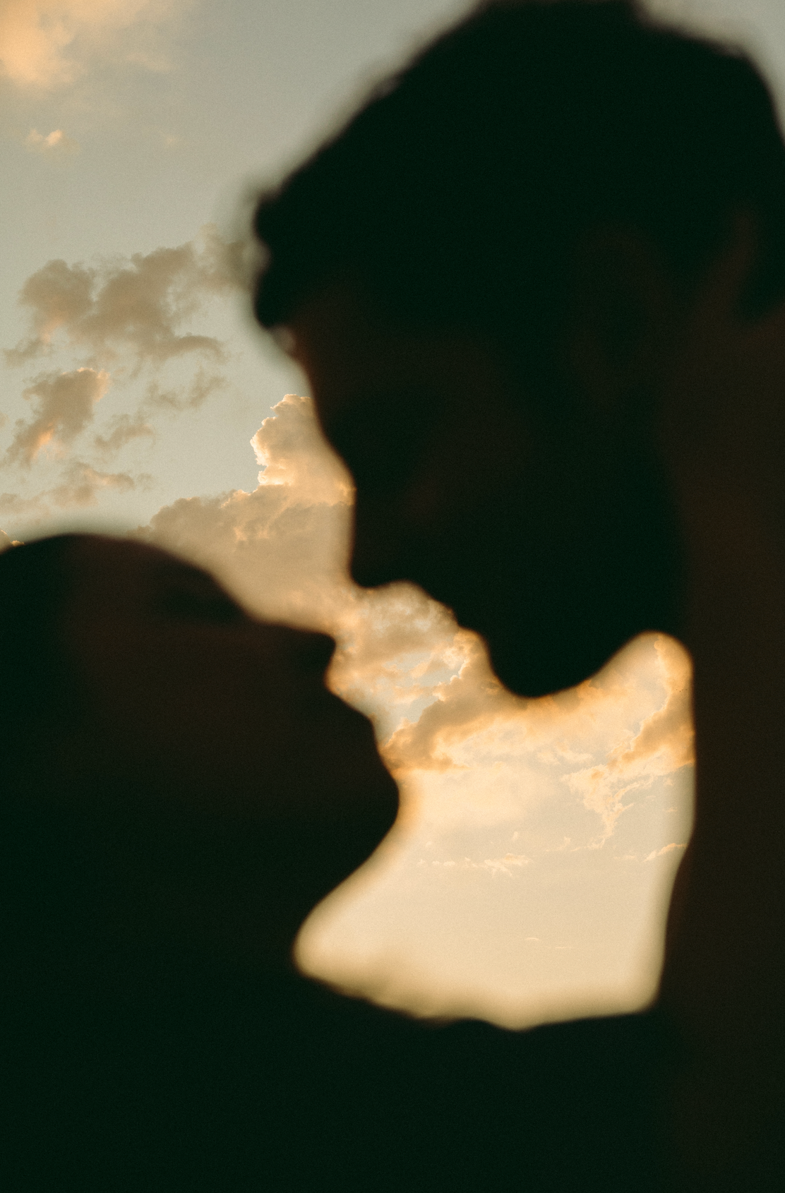 Silhouetted figures in an intimate moment against a warm sunset backdrop.