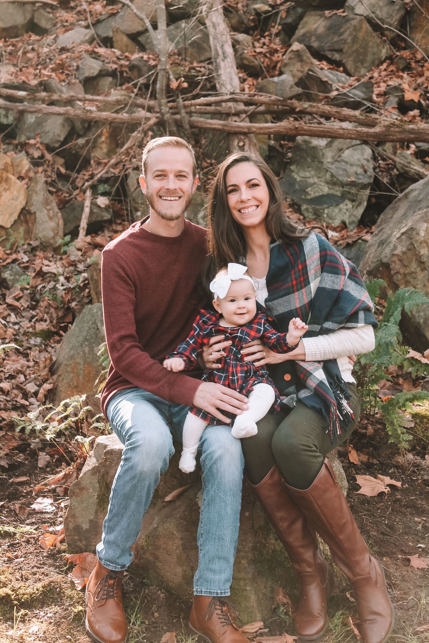 Fall family portrait on rocky outcrop in coordinated autumn-colored outfits.