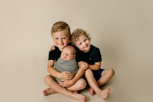 Family members sitting together and embracing on neutral background.