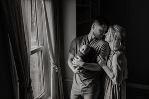 Black and white silhouettes of family sharing intimate moment near window.
