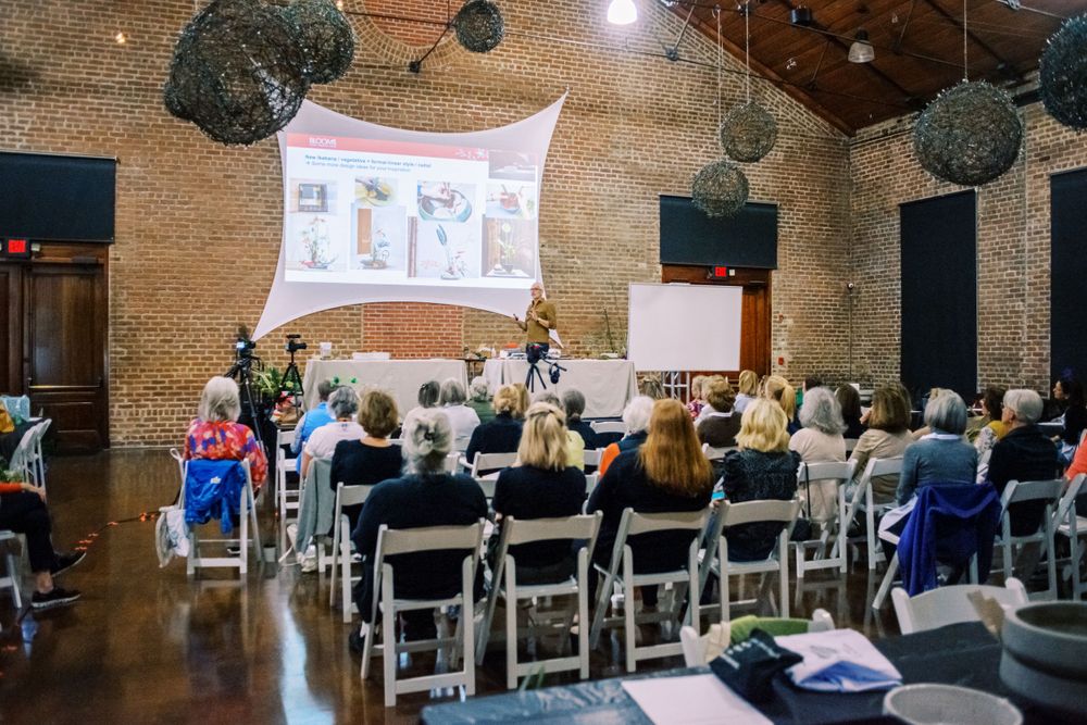 Event venue with audience watching presentation on projector screen with decorative lighting.
