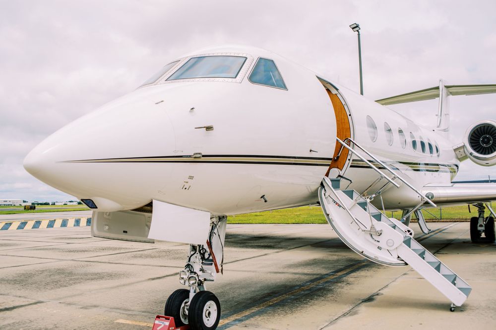 A luxurious private jet parked on tarmac with boarding stairs extended.