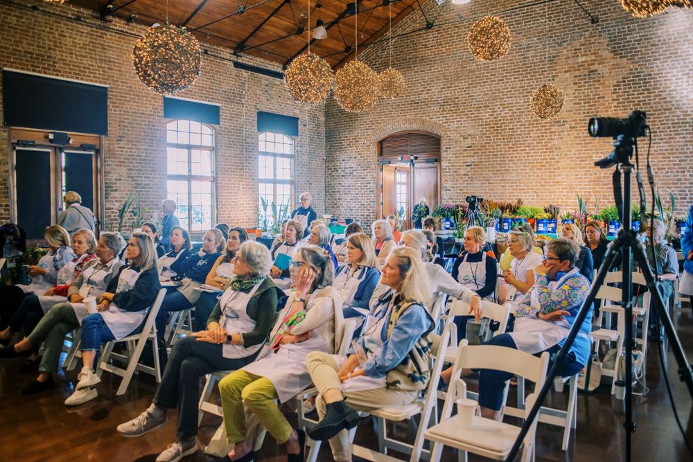 Conference room filled with attendees seated in rows under decorative spherical light fixtures.