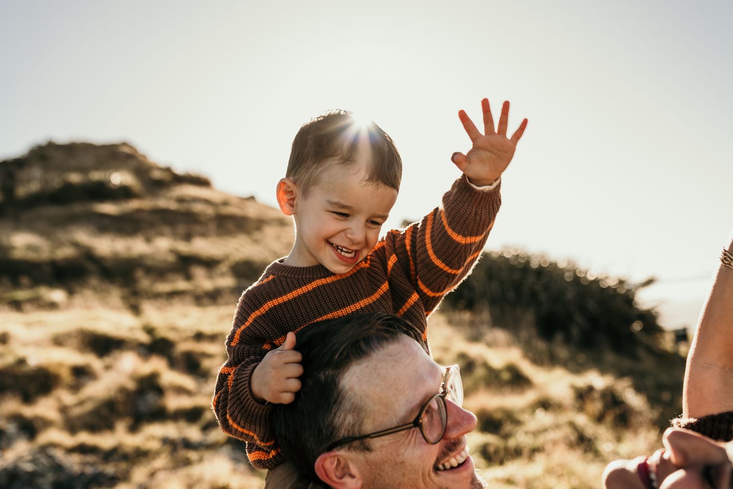 A joyful moment captured outdoors with lifted arms against a mountainous backdrop.