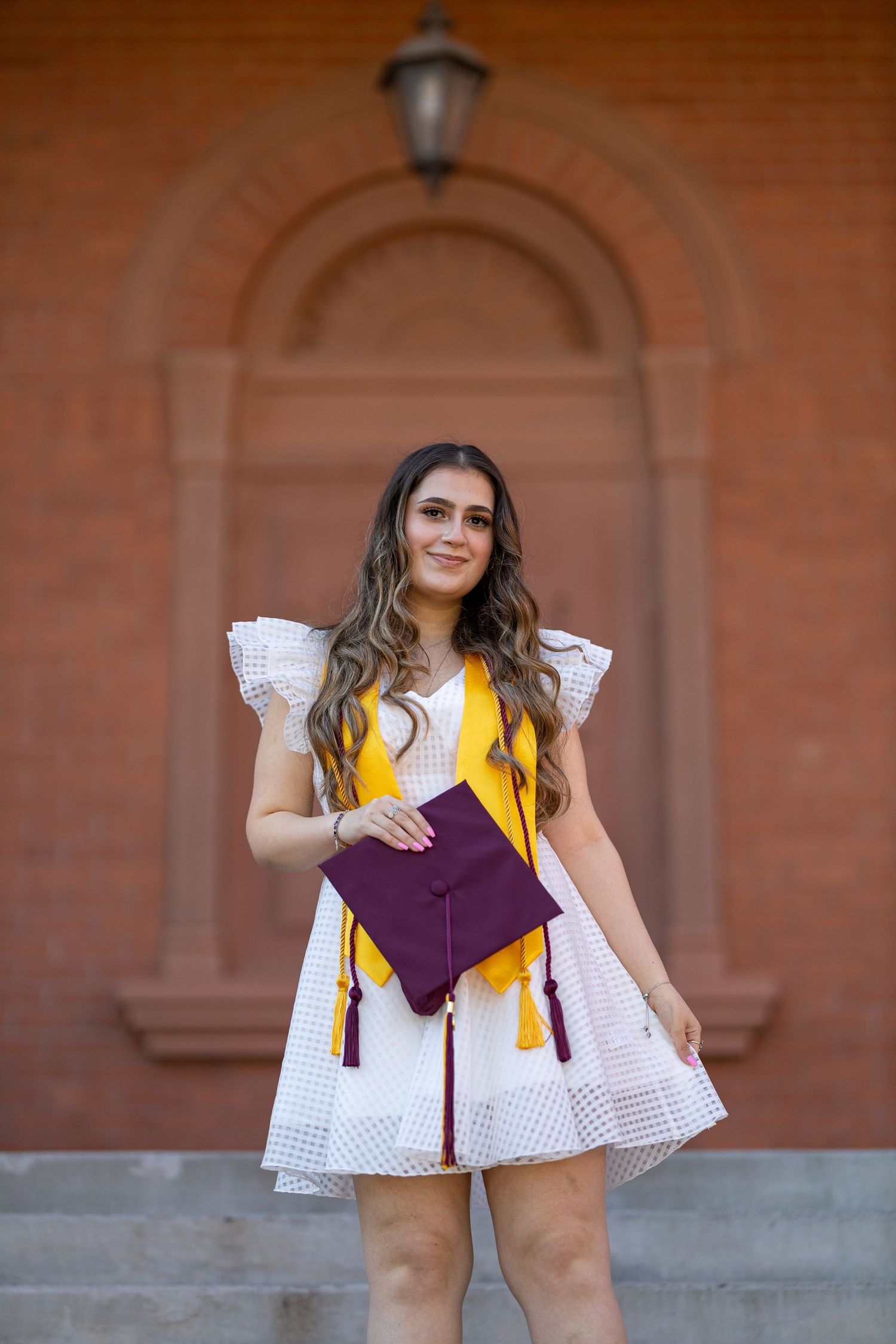 College Senior holding her cap and gown posing for her senior pictures.