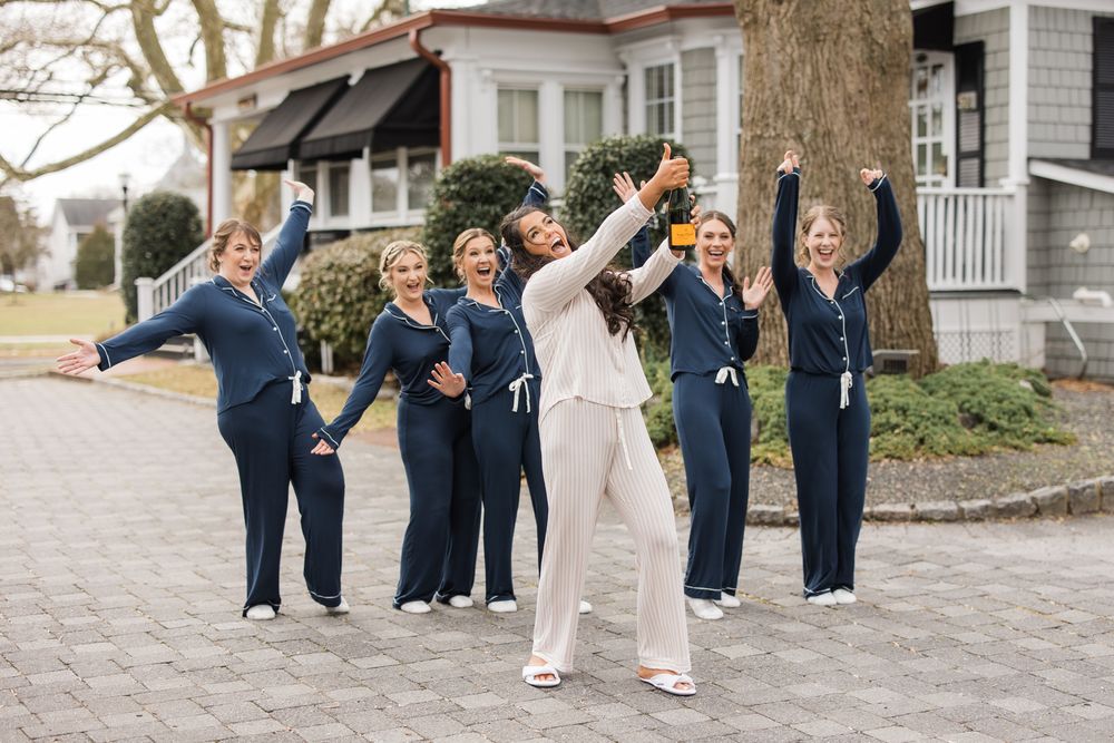 Wedding party in matching navy outfits striking fun poses outdoors.