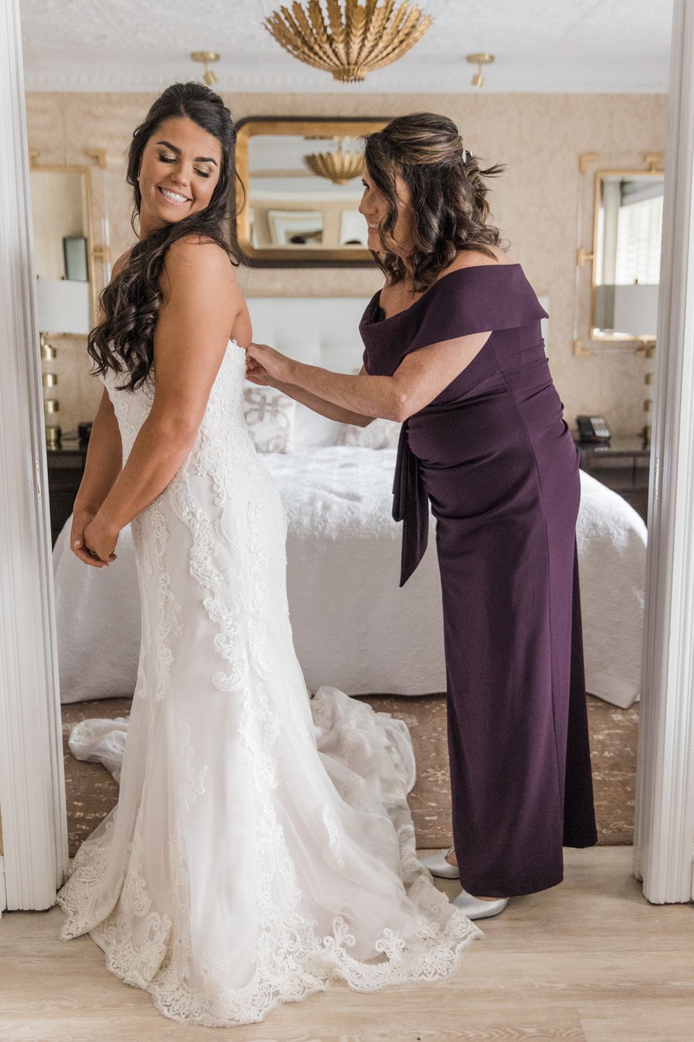 Final wedding dress adjustments being made in elegant dressing room.
