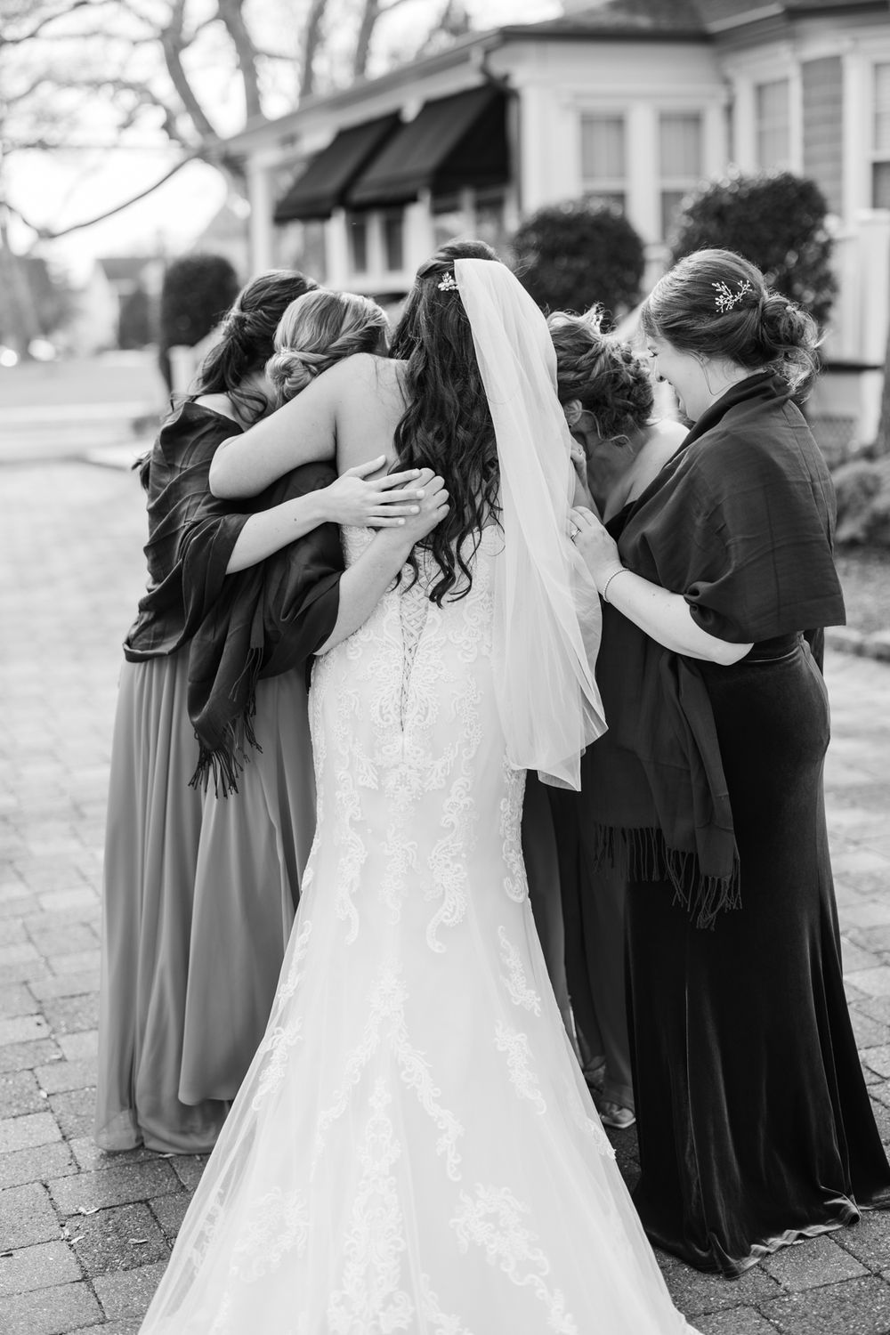 A touching moment captured as wedding party members embrace in a group hug on stone path.