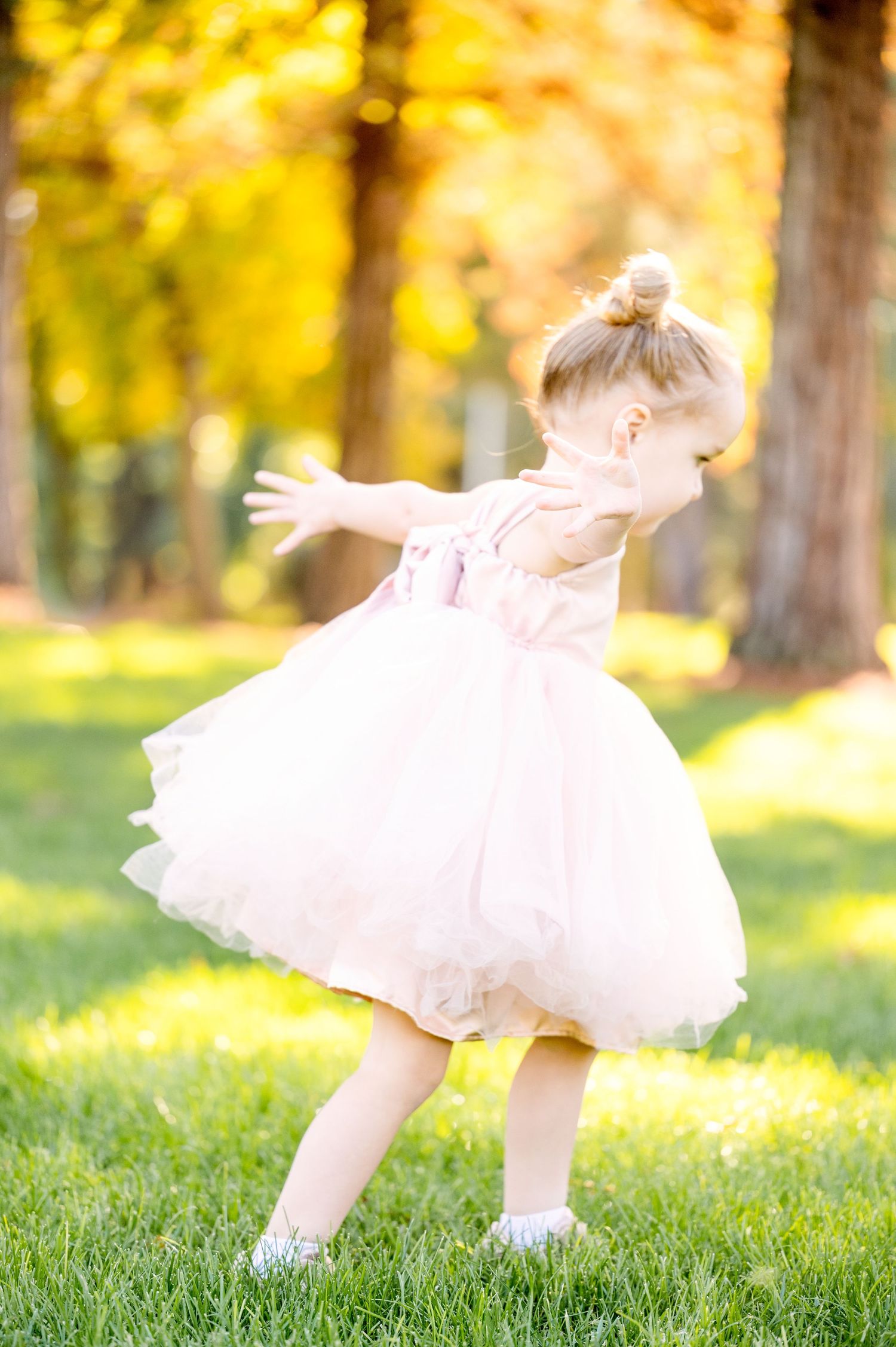 Dancing figure in pink tulle captured against golden autumn foliage and grass.
