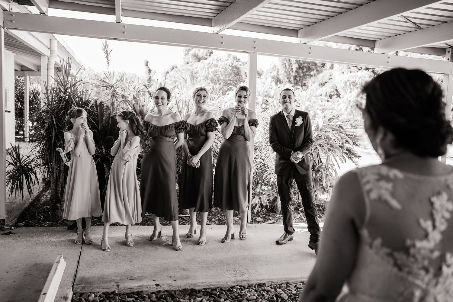 Wedding party poses together under a covered porch during black and white celebration photo.