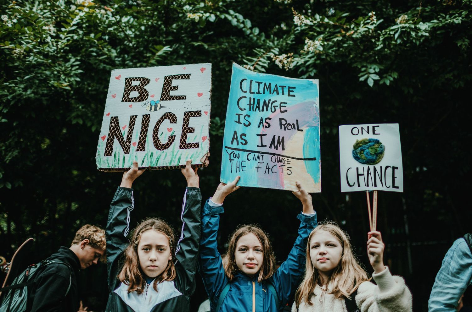 three young students hold signs above their heads at Portland Climate Strike photojournalism