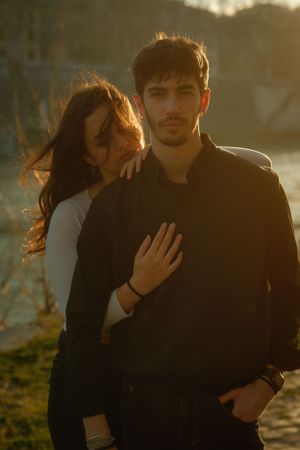 Romantic couple pose together in warm sunset light outdoors.