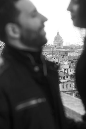 A black and white cityscape featuring St. Peter's Dome in Rome with silhouettes in the foreground.