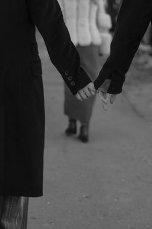 Close-up black and white photo of two people holding hands.