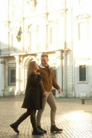 A couple dancing in front of a historic European building at sunset.